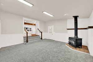 Carpeted living room featuring a wood stove and stairs