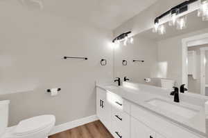 Bathroom featuring baseboards, a sink, toilet, and wood finished floors