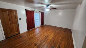 Spare room featuring a ceiling fan, dark wood-style flooring, and baseboards