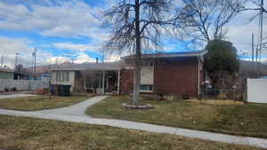 View of front of property with fence, a front lawn, and brick siding