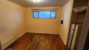 Unfurnished room with dark wood-type flooring and baseboards