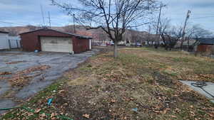 View of yard featuring an outdoor structure, driveway, a detached garage, and fence