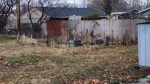 View of yard featuring central AC unit and fence