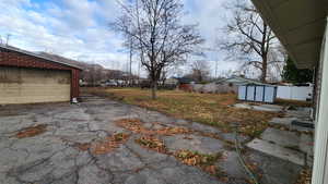 View of yard with a storage shed, fence, and an outbuilding