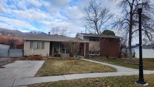 View of front of home featuring a front yard, brick siding, fence, and a mountain view