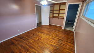 Unfurnished bedroom featuring a ceiling fan, dark wood-style flooring, connected bathroom, and baseboards