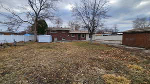 Rear view of house featuring an outbuilding, a storage unit, a fenced backyard, and brick siding