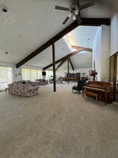 Living room with lofted ceiling with beams, ceiling fan, a textured ceiling, and carpet