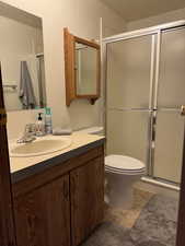 Bathroom featuring toilet, tile patterned floors, an enclosed shower, and vanity