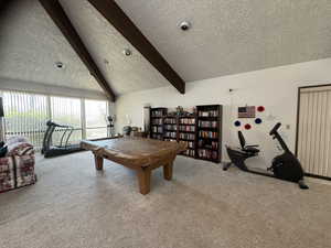 Game room with carpet floors, lofted ceiling with beams, and a textured ceiling