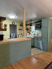 Kitchen featuring light wood-style floors, stainless steel microwave, open shelves, and a sink