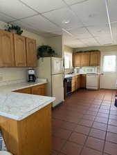 Kitchen featuring brown cabinets, white appliances, light countertops, and plenty of natural light