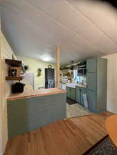 Kitchen featuring open shelves, light wood-style floors, freestanding refrigerator, butcher block countertops, and a peninsula