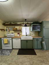 Kitchen featuring white appliances, light countertops, a sink, and green cabinetry