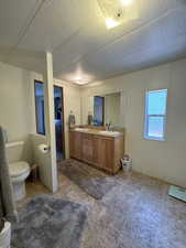 Full bath featuring a textured ceiling, double vanity, and a sink