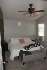 Carpeted bedroom with lofted ceiling, ceiling fan, cooling unit, and visible vents