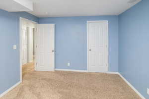 Unfurnished bedroom featuring light carpet and baseboards