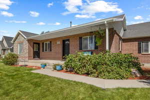 Ranch-style house featuring a porch, brick siding, and a front lawn