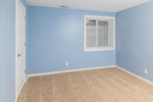 Carpeted empty room featuring visible vents and baseboards