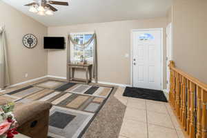 Entrance foyer with light tile patterned floors, ceiling fan, lofted ceiling, and baseboards