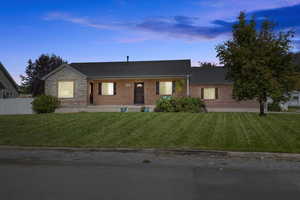 Ranch-style house featuring brick siding, fence, and a yard