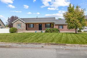 Ranch-style house with a front yard, brick siding, and fence