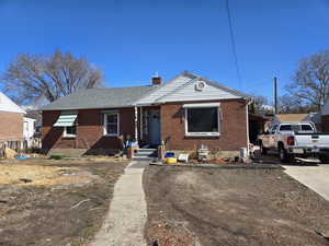 View of front of home featuring roof with shingles, a chimney, and brick siding