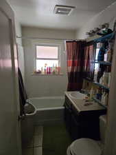 Full bathroom with toilet, tile patterned flooring, shower / bath combo, and visible vents