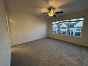 Spare room featuring dark colored carpet, ceiling fan, a textured ceiling, and baseboards