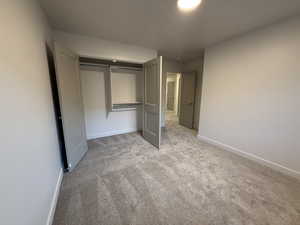 Unfurnished bedroom featuring a closet, light carpet, and baseboards
