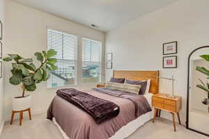 Bedroom featuring light carpet, visible vents, and baseboards