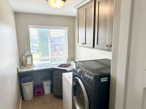 Clothes washing area with cabinet space and a sink