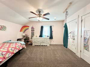 Bedroom with lofted ceiling, dark colored carpet, and a ceiling fan