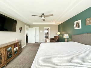 Bedroom featuring a tray ceiling, carpet, a ceiling fan, and baseboards