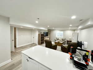 Kitchen with open floor plan, light countertops, light wood-type flooring, white cabinetry, and recessed lighting