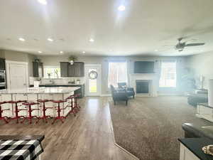 Living room featuring a fireplace, baseboards, a ceiling fan, and recessed lighting