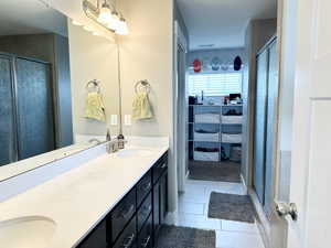 Full bath with tile patterned floors, a sink, a shower stall, and double vanity