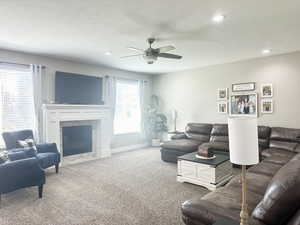 Living area with ceiling fan, recessed lighting, carpet flooring, baseboards, and a brick fireplace