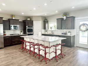 Kitchen featuring appliances with stainless steel finishes, a breakfast bar, light stone counters, a center island, and a sink