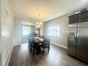 Dining room with dark wood-style floors, baseboards, and a chandelier