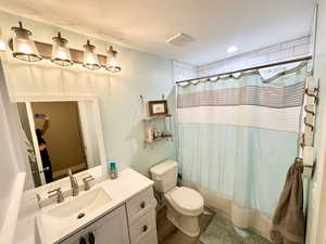 Full bath featuring curtained shower, visible vents, vanity, and toilet