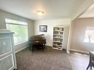 Living area with wood walls, baseboards, a textured ceiling, and wood finished floors