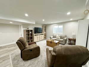 Living area featuring baseboards, light wood-style flooring, and recessed lighting