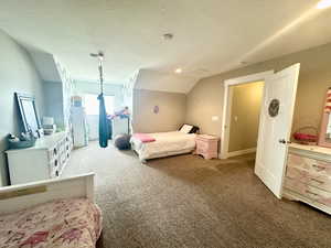 Carpeted bedroom featuring vaulted ceiling and a textured ceiling