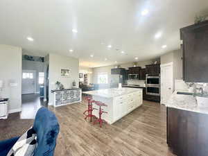 Kitchen featuring appliances with stainless steel finishes, a center island, a sink, white cabinetry, and backsplash