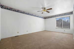 Unfurnished room featuring light carpet, baseboards, visible vents, and a ceiling fan