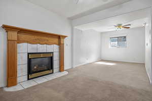 Unfurnished living room with baseboards, light colored carpet, ceiling fan, and a tiled fireplace