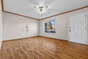 Interior space with ornamental molding, light wood finished floors, a ceiling fan, and baseboards