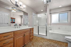 Bathroom featuring a garden tub, visible vents, a textured ceiling, and vanity