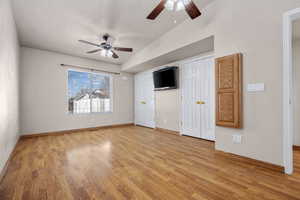 Unfurnished bedroom featuring baseboards, a ceiling fan, a textured ceiling, light wood-type flooring, and two closets